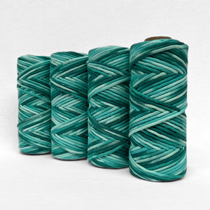 flour rolls of hand painted string in colour blue lagoon which consist of deep green and bright blue standing side by side angled on white back drop