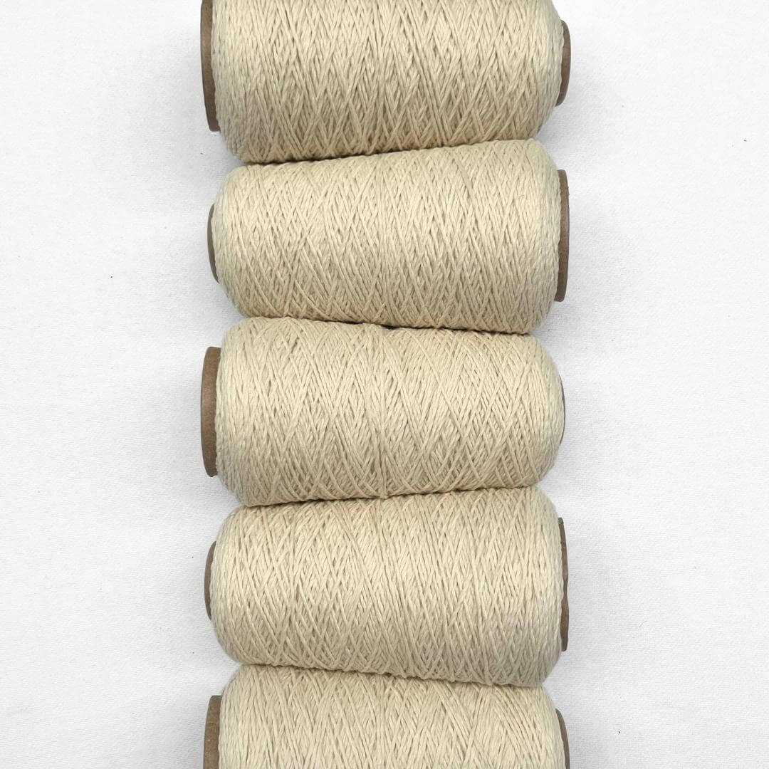 seven rolls of woollen yarn in different colours standing in triangle formation on white background