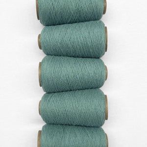 Five rolls of teal blue wool cord in flat lay image laying side by side on white background 