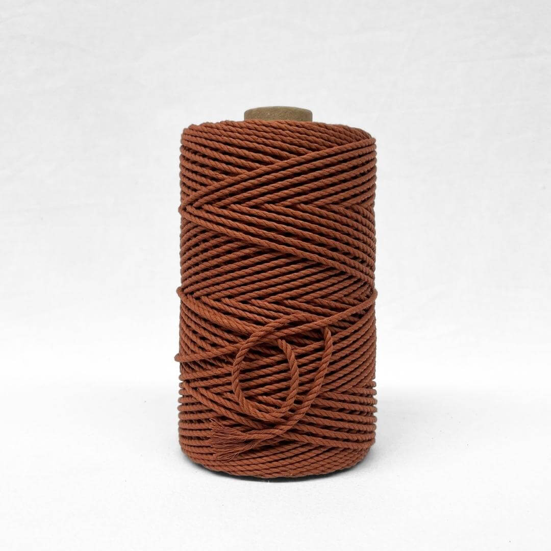 single roll of a red rust 4mm 3ply macrame cord in whtie background