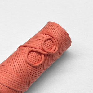 singel roll of coral crush cloud 9 cotton cord laying flat on white background