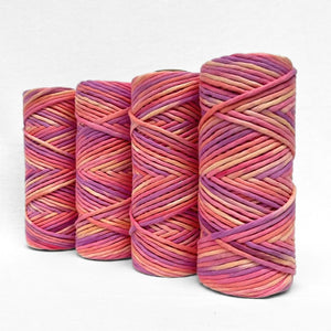 four rolls of hand painted string on coral reef colour way consisitng of coral, pink,purple and yellow stand upright on white background