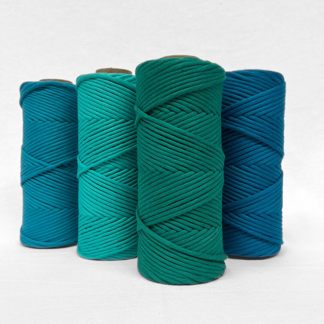 one roll of cotton cord for macrame weaving diy craft in colour mykonos blue laying flat and angled on white background